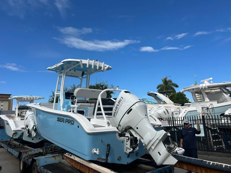 Slide: The Image of 2025 Sea Pro 225 Sandbar boat with Suzuki engine on trailer under clear blue sky. - 2