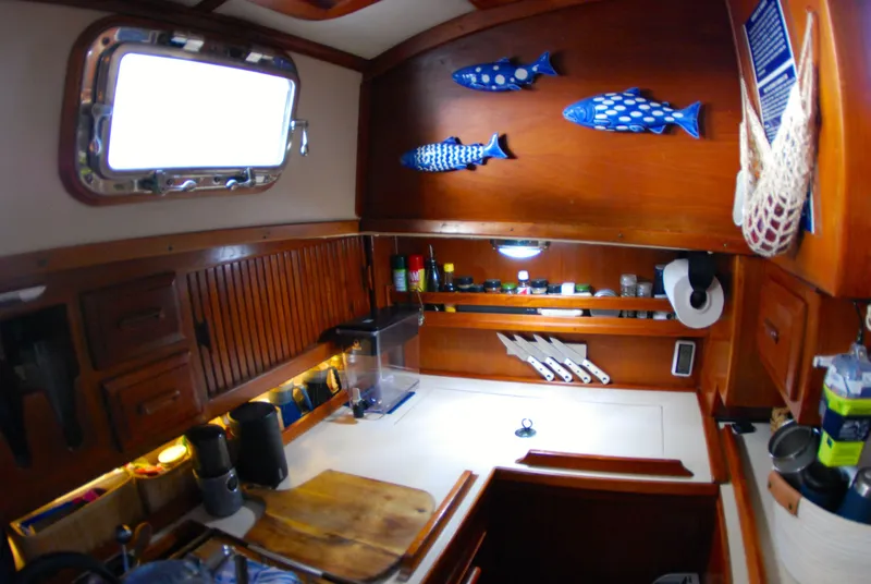 Slide: The Image of Cozy 1985 Endeavour 38 yacht galley with wooden cabinets, fish decor, and organized kitchen essentials. - 37