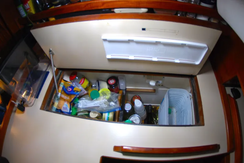 Slide: The Image of Storage compartment in 1985 Endeavour 38 yacht, filled with various food items and containers. - 39