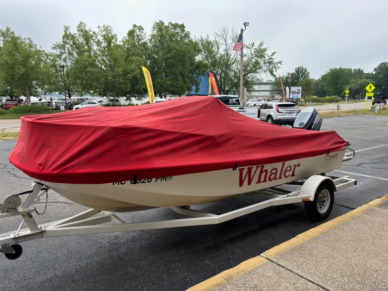 Slide: The Image of 1993 Boston Whaler 17 Montauk boat with red cover on a trailer in a parking lot. - 15