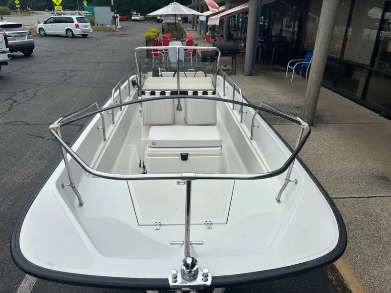Slide: The Image of 1993 Boston Whaler 17 Montauk boat parked near a restaurant, showcasing its open deck design. - 6