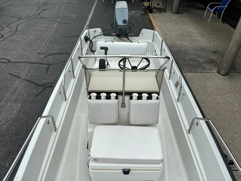 Slide: The Image of 1993 Boston Whaler 17 Montauk boat with seating and steering console, parked on pavement. - 7