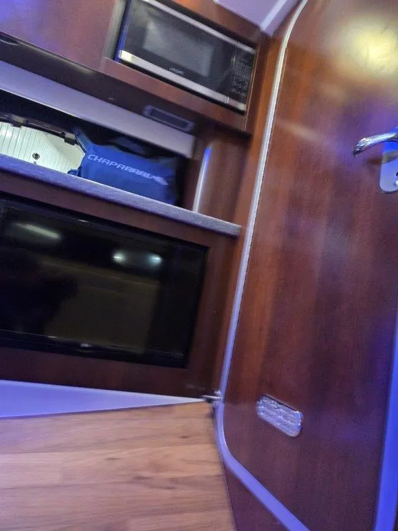 Slide: The Image of Interior of 2022 Chaparral 347 SSX with microwave, TV, and wooden cabinetry. - 26