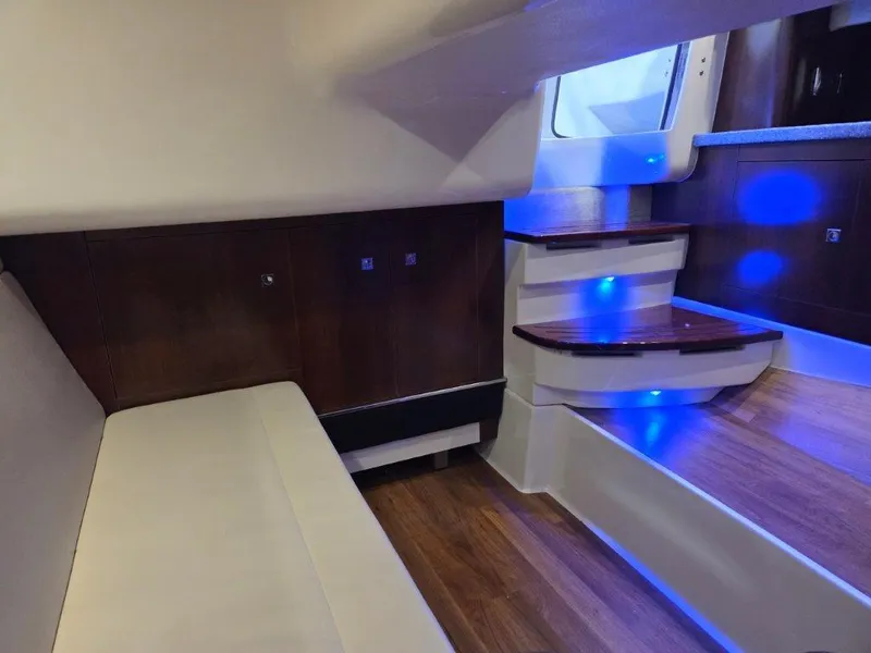 Slide: The Image of 2022 Chaparral 347 SSX interior with wooden steps, ambient blue lighting, and cushioned seating. - 28