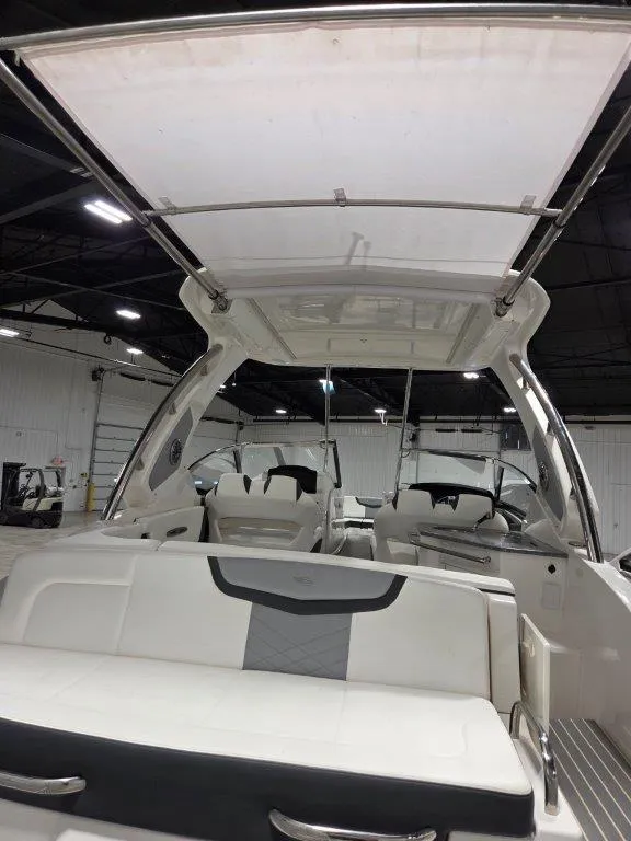 Slide: The Image of 2022 Chaparral 347 SSX boat interior with seating and canopy in a warehouse setting. - 32