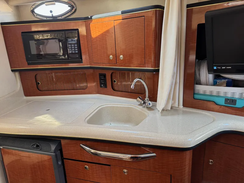 Slide: The Image of 2002 Sea Ray 300 Sundancer kitchen with microwave, sink, and wooden cabinetry. - 10