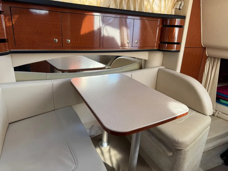 Slide: The Image of Interior of 2002 Sea Ray 300 Sundancer with dining area and wooden cabinetry. - 13