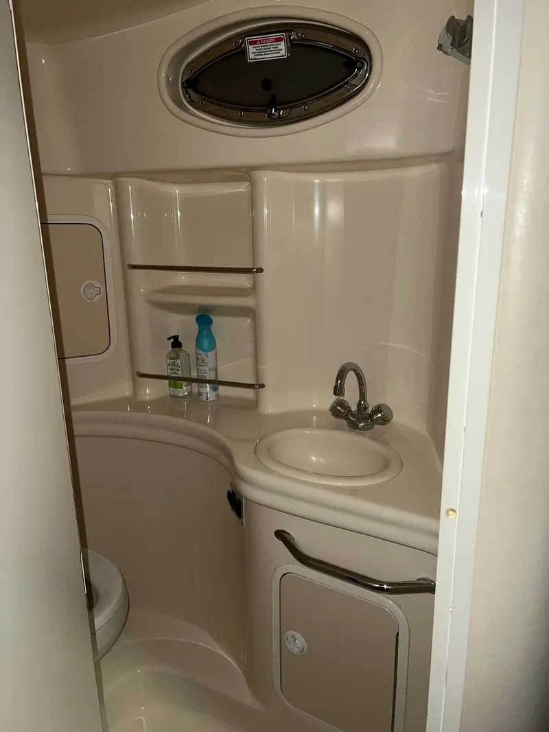 Slide: The Image of 2002 Sea Ray 300 Sundancer bathroom with sink, storage, and porthole window. - 14