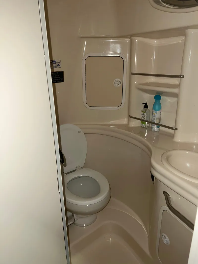Slide: The Image of Bathroom interior of 2002 Sea Ray 300 Sundancer boat, featuring toilet and shelves. - 15