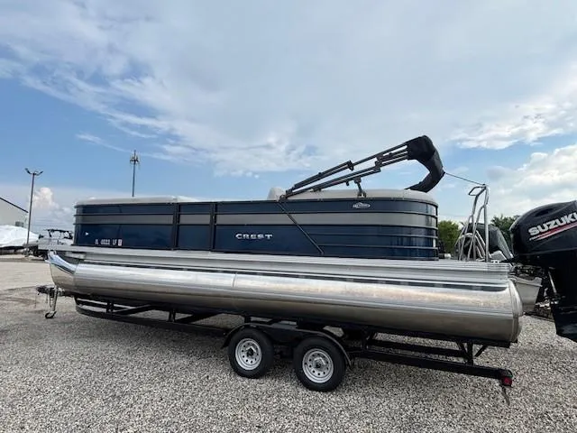 Slide: The Image of 2020 Crest Classic DLX 240 SLC pontoon boat on trailer, parked on gravel. - 2