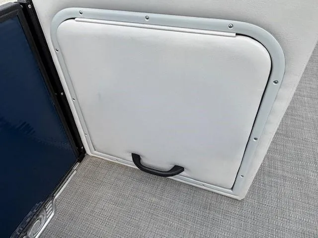 Slide: The Image of Crest Classic DLX 240 SLC 2020 boat storage compartment with handle on carpeted floor. - 9