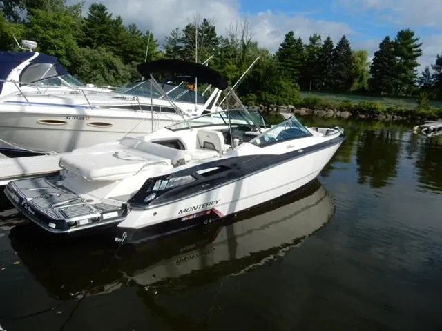 Slide: The Image of 2014 Monterey 288 Super Sport boat docked on calm water, surrounded by trees. - 17