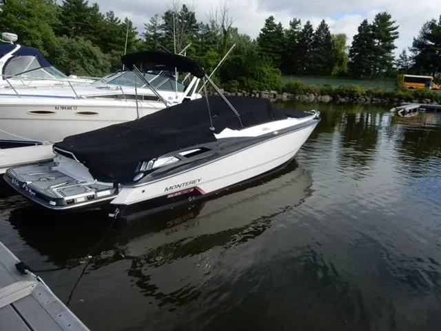 Slide: The Image of 2014 Monterey 288 Super Sport boat docked with black cover, surrounded by trees and water. - 9