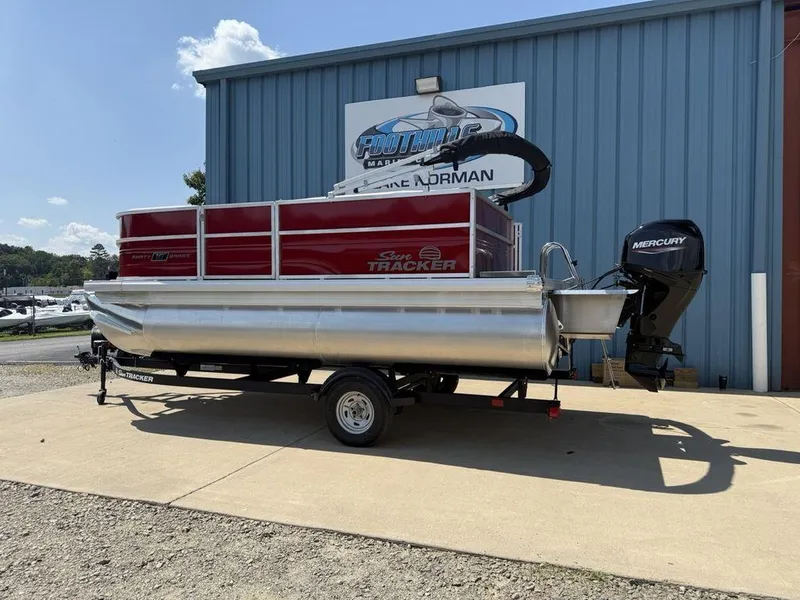Slide: The Image of 2026 Sun Tracker PARTY BARGE® 16 DLX pontoon boat on trailer, parked outside dealership. - 8