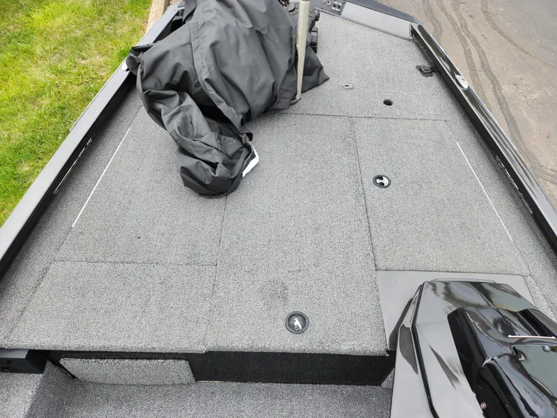 Slide: The Image of 2021 Vexus AVX189 boat deck with storage compartments and cover, parked on pavement. - 14