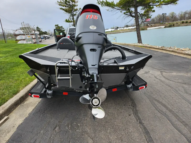 Slide: The Image of 2021 Vexus AVX189 boat with outboard motor, parked near a lake on a paved road. - 2