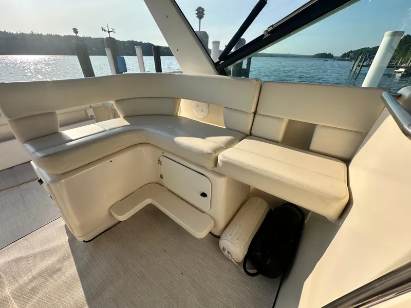Slide: The Image of 1997 Tiara Yachts 3100 Open interior with cream seating, docked by a scenic waterfront. - 13
