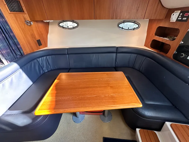 Slide: The Image of Interior of a 1997 Tiara Yachts 3100 Open with a wooden table and blue seating. - 16