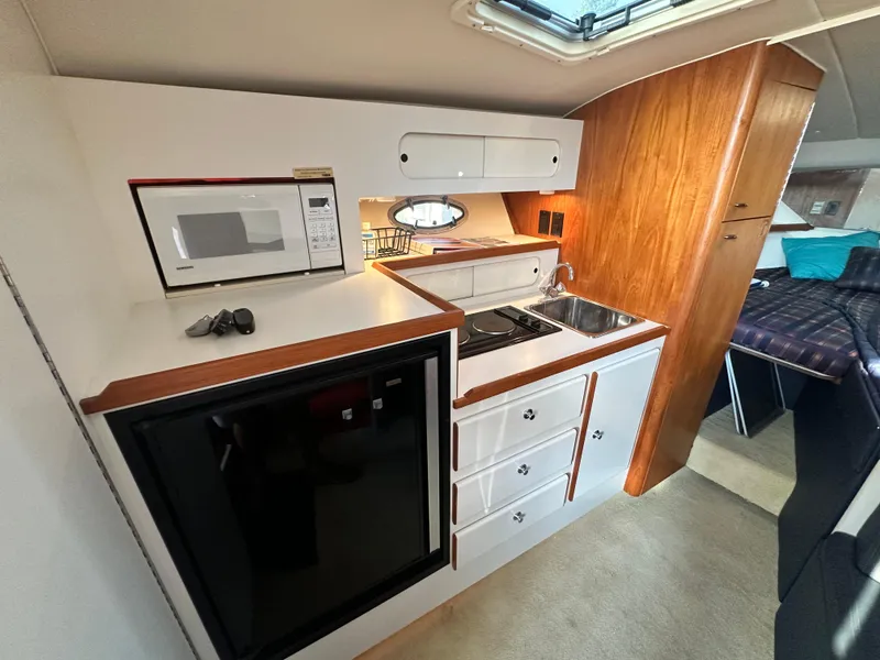 Slide: The Image of 1997 Tiara Yachts 3100 Open interior kitchen with microwave, sink, and storage cabinets. - 19