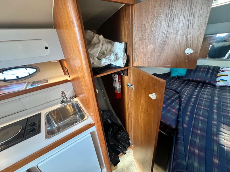 Slide: The Image of 1997 Tiara Yachts 3100 Open interior with kitchenette, bed, and storage cabinets. - 21