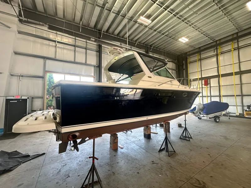 Slide: The Image of 1997 Tiara Yachts 3100 Open in a warehouse, elevated on stands for maintenance. - 3