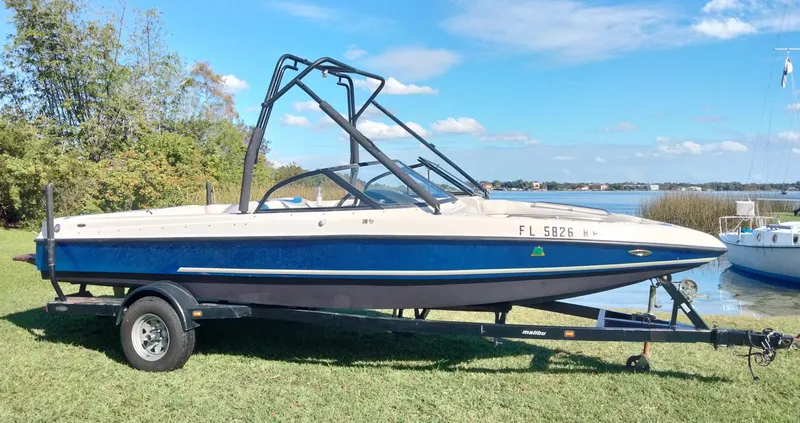 The Image of 2001 Tigé 21i boat on trailer by a lake, under a clear blue sky. - 1