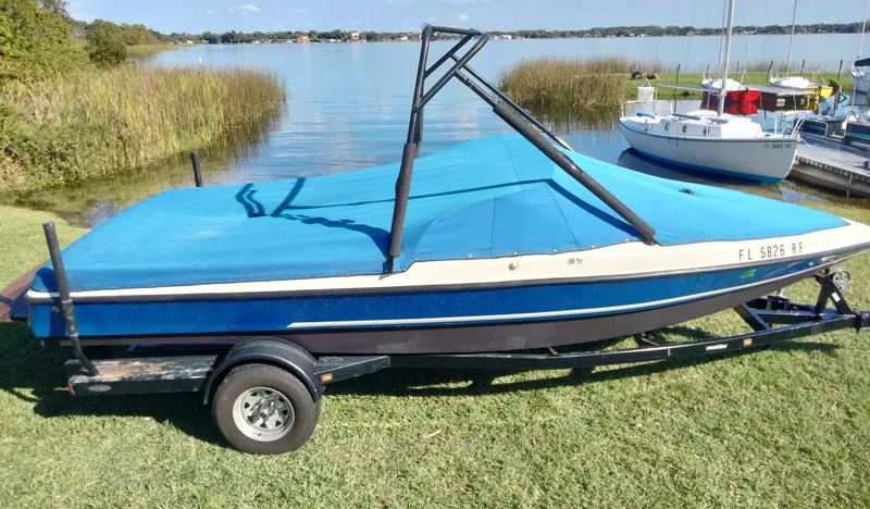 Slide: The Image of 2001 Tigé 21i boat on trailer by a lake, covered with a blue tarp. - 12