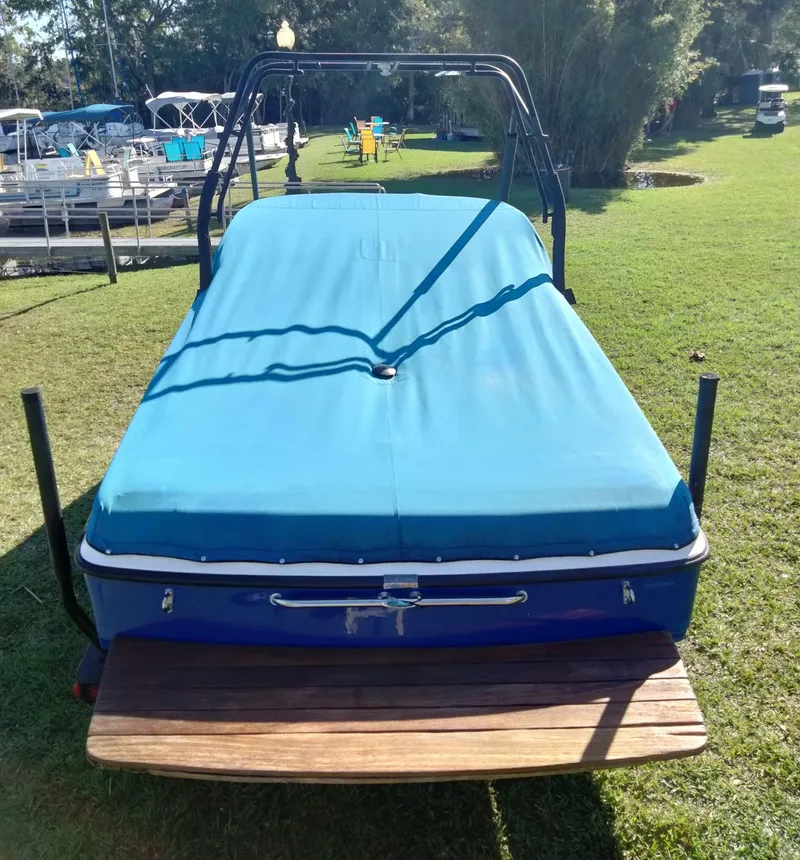 Slide: The Image of 2001 Tigé 21i boat with blue cover on grassy area near docks. - 13