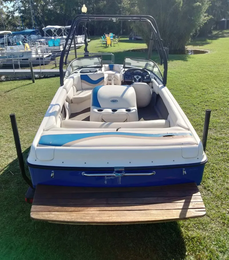 Slide: The Image of 2001 Tigé 21i boat with open seating, parked on grass near docks. - 6