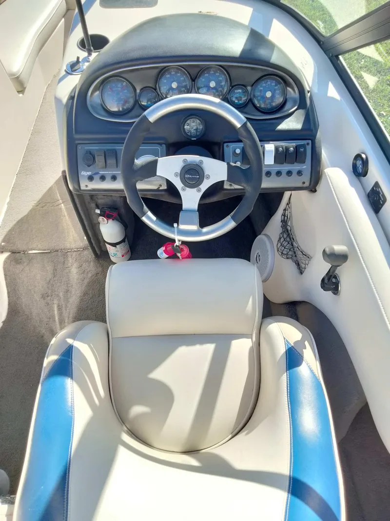 Slide: The Image of 2001 Tigé 21i boat dashboard with steering wheel and gauges, featuring beige and blue seating. - 8
