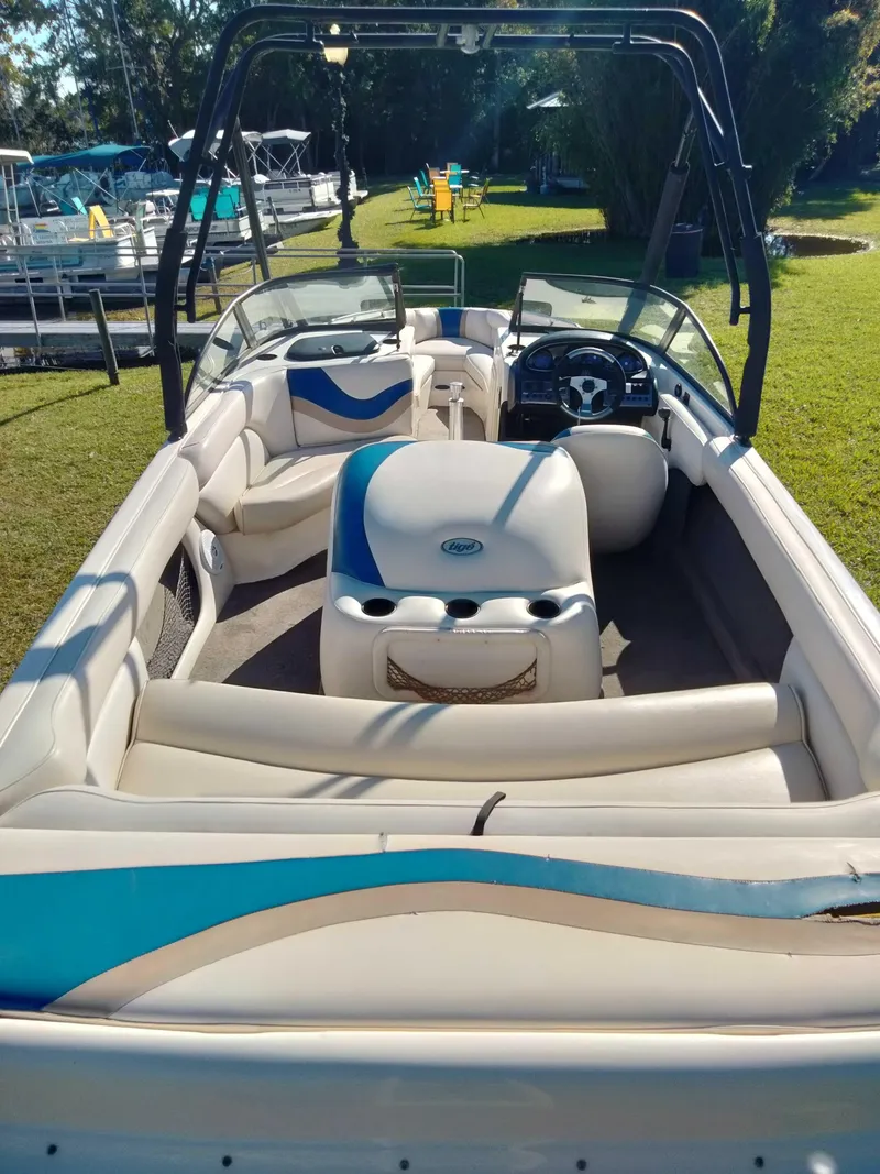 Slide: The Image of 2001 Tigé 21i boat interior with seating and steering wheel, parked on grass. - 9