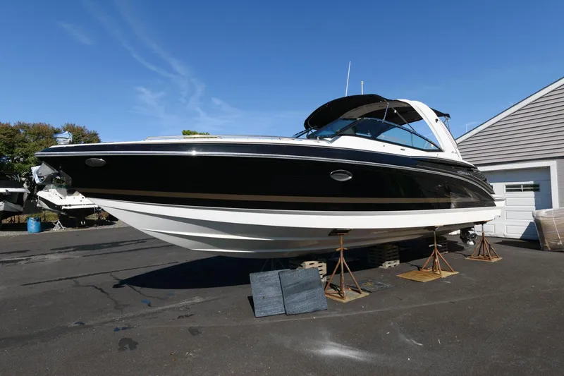 Slide: The Image of 2016 Formula 330 Crossover Bowrider boat on stands, black and white exterior, sunny day. - 2