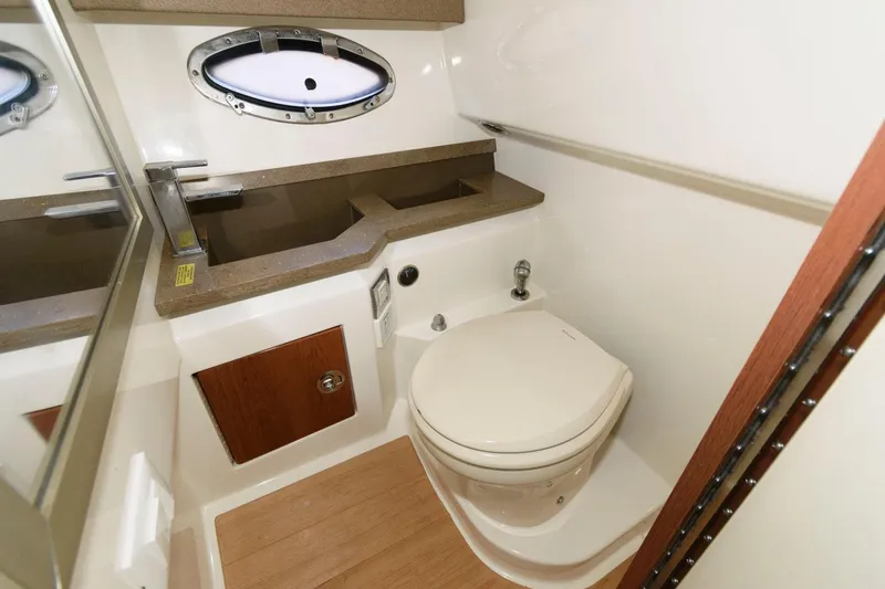 Slide: The Image of 2016 Formula 330 Crossover Bowrider bathroom with toilet, sink, and porthole window. - 21