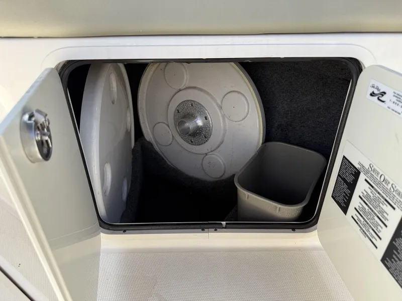 Slide: The Image of Storage compartment in a 2005 Sea Ray 240 Sundeck boat, featuring a trash bin and table. - 27