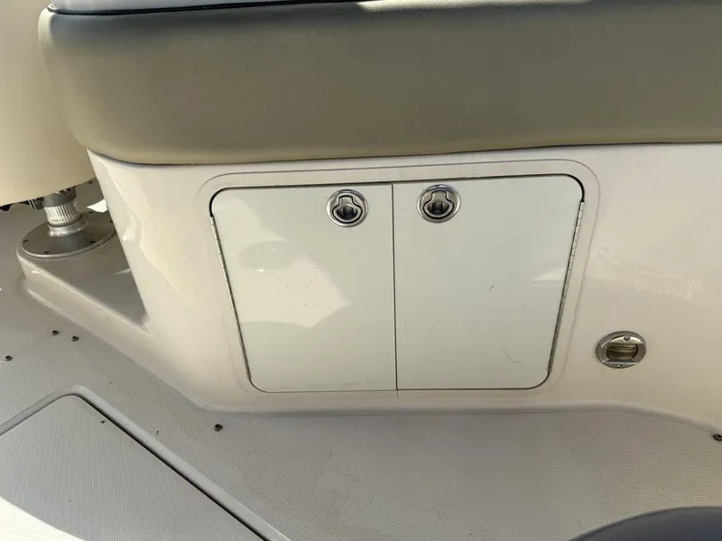 Slide: The Image of 2005 Sea Ray 240 Sundeck storage compartment with dual latches and cushioned seating. - 31