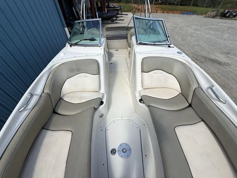 Slide: The Image of 2005 Sea Ray 240 Sundeck interior with beige seating and dual windshields. - 34