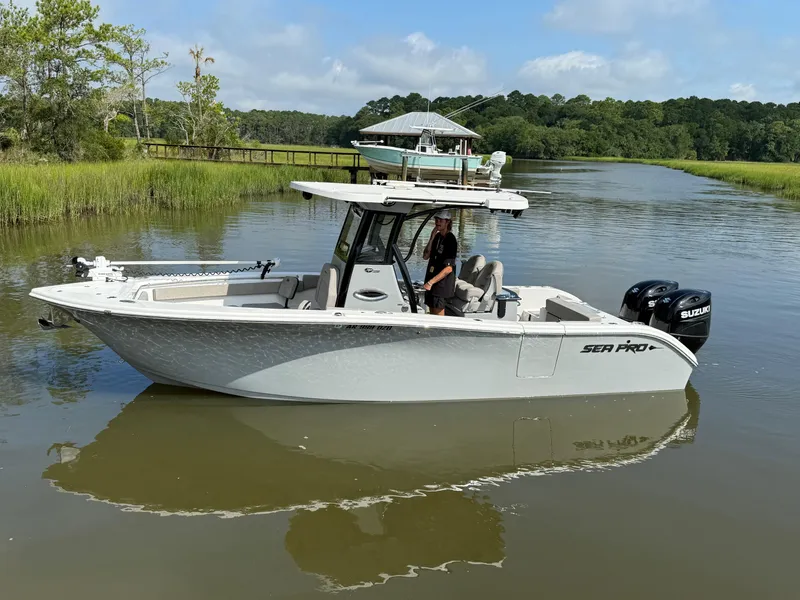 The Image of 2024 Sea Pro 262DLX boat on a calm river with lush greenery. - 0