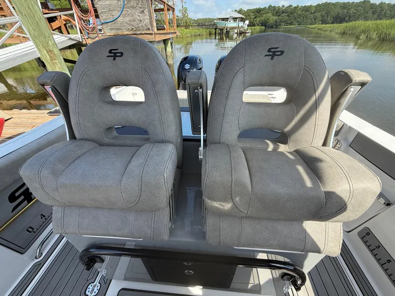 Slide: The Image of 2024 Sea Pro 262DLX boat seats, gray upholstery, docked by a scenic waterway. - 19