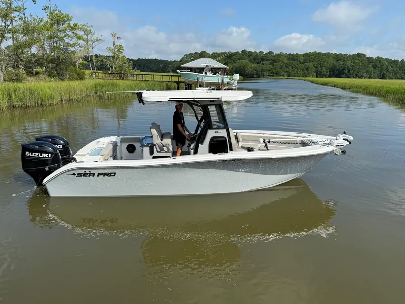 Slide: The Image of 2024 Sea Pro 262DLX boat on calm water, featuring dual Suzuki engines. - 2