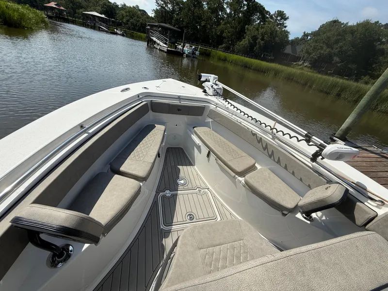 Slide: The Image of 2024 Sea Pro 262DLX boat interior with cushioned seating, docked by a serene waterway. - 20
