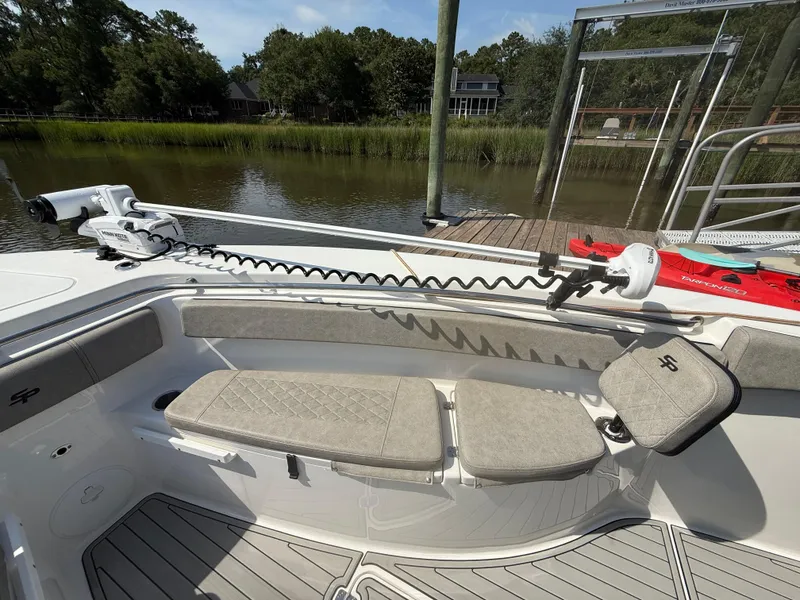 Slide: The Image of 2024 Sea Pro 262DLX boat interior with seating and trolling motor, docked by a serene waterfront. - 21