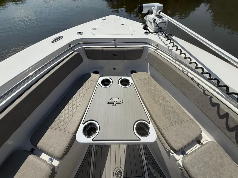 Slide: The Image of 2024 Sea Pro 262DLX boat interior with cushioned seating and table, on calm water. - 23