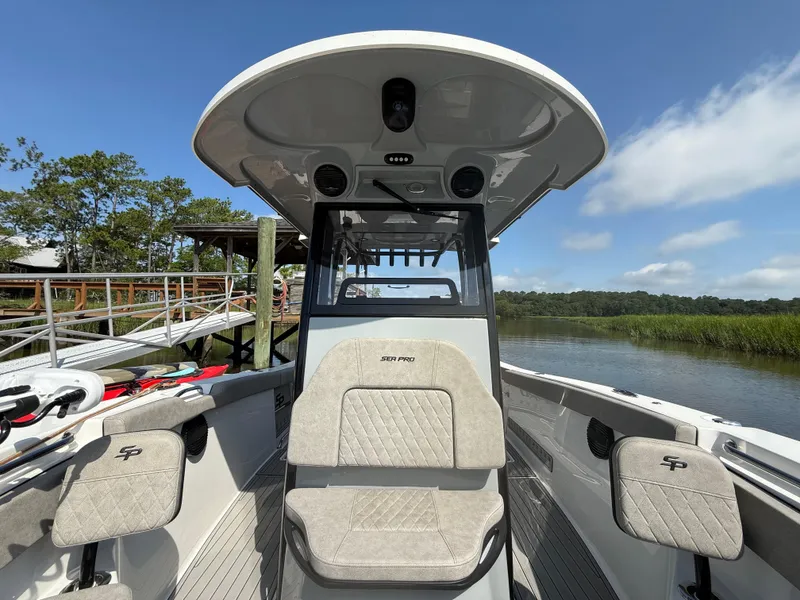 Slide: The Image of 2024 Sea Pro 262DLX boat interior with seating, docked by a scenic river. - 26