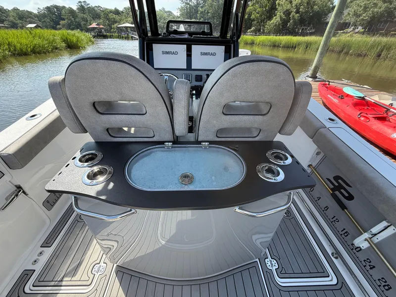 Slide: The Image of 2024 Sea Pro 262DLX boat interior with seating, cup holders, and Simrad electronics. - 29
