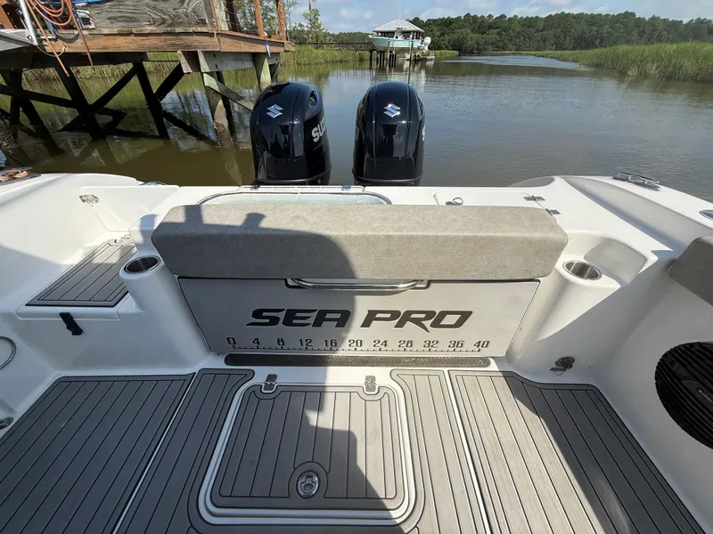 Slide: The Image of 2024 Sea Pro 262DLX boat with dual Suzuki engines, docked by a wooden pier. - 31