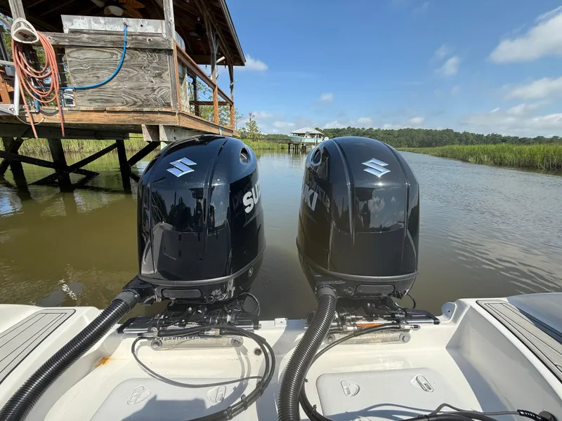 Slide: The Image of Twin Suzuki outboard engines on a 2024 Sea Pro 262DLX boat near a wooden dock. - 33