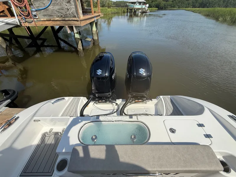 Slide: The Image of 2024 Sea Pro 262DLX boat with dual Suzuki outboard motors on a calm river. - 34