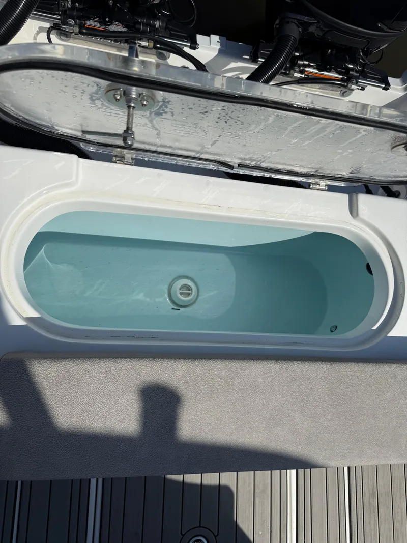 Slide: The Image of 2024 Sea Pro 262DLX livewell with open lid, showcasing interior water compartment. - 35