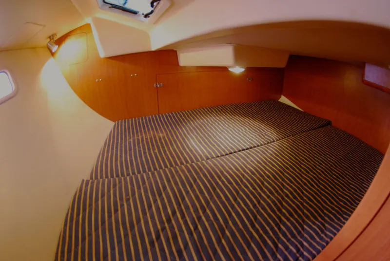 Slide: The Image of 2008 Hunter 33 yacht cabin interior with striped bedding and wooden paneling. - 21