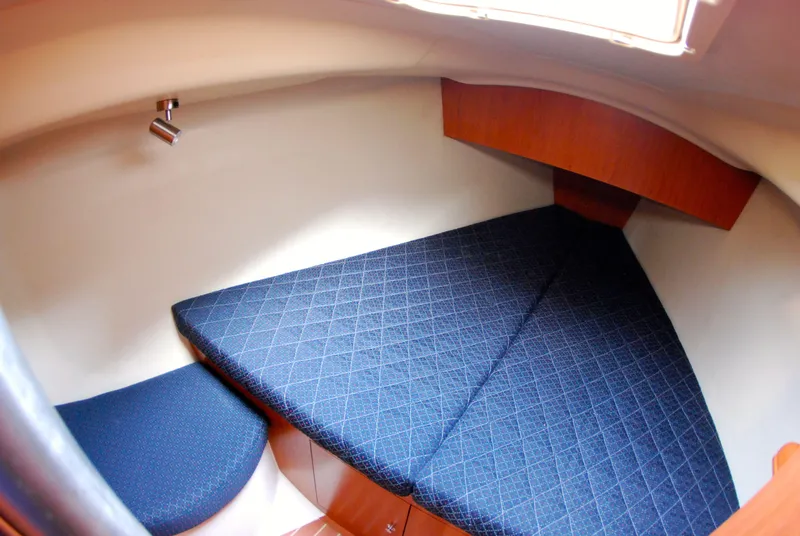 Slide: The Image of 2008 Hunter 33 yacht interior cabin with blue cushioned V-berth and wooden accents. - 30